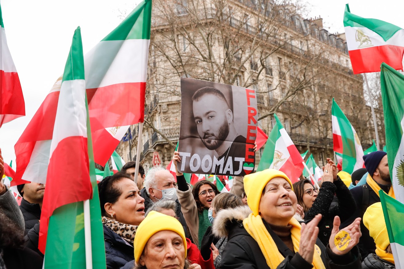 A woman holds a portrait of Iranian rapper Toomaj Salehi in Paris.