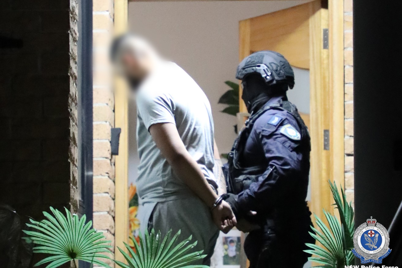 A man is arrested during a police raid on a Sydney home. 