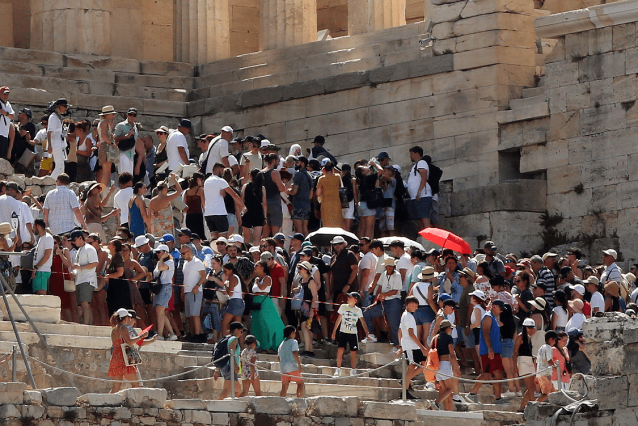 Tourists leave the Acropolis in Athens after the site was forced to close by the unprecedented heat.