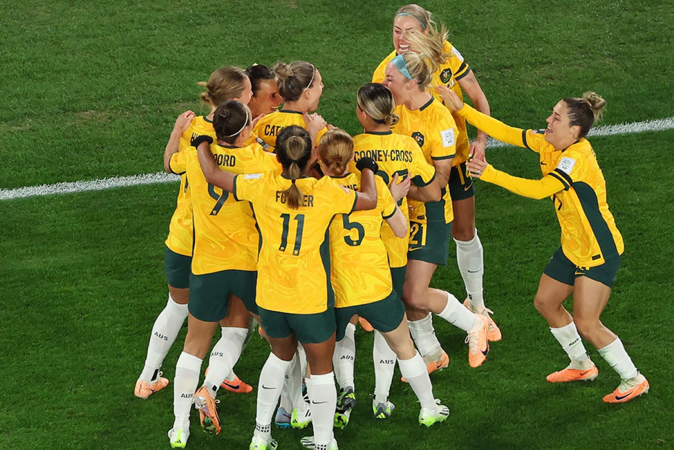 Teammates mob acting captain Steph Catley after her penalty at Stadium Australia in Sydney on Thursday night. 