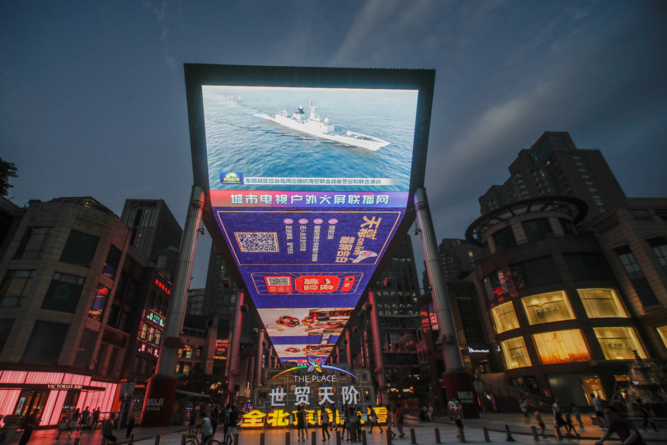 A giant TV screen in Beijing flashes propaganda images of a Chinese aircraft carrier off the Taiwan coast.