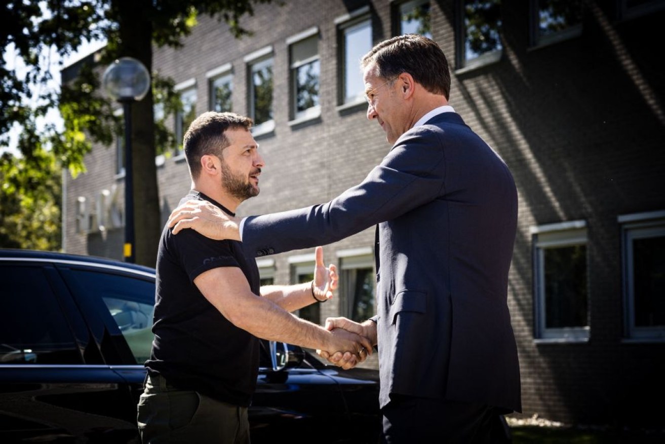 Ukrainian President Volodymyr Zelensky (L) and outgoing Dutch Prime Minister Mark Rutte shake hands during a visit to the Eindhoven Military Air Base.