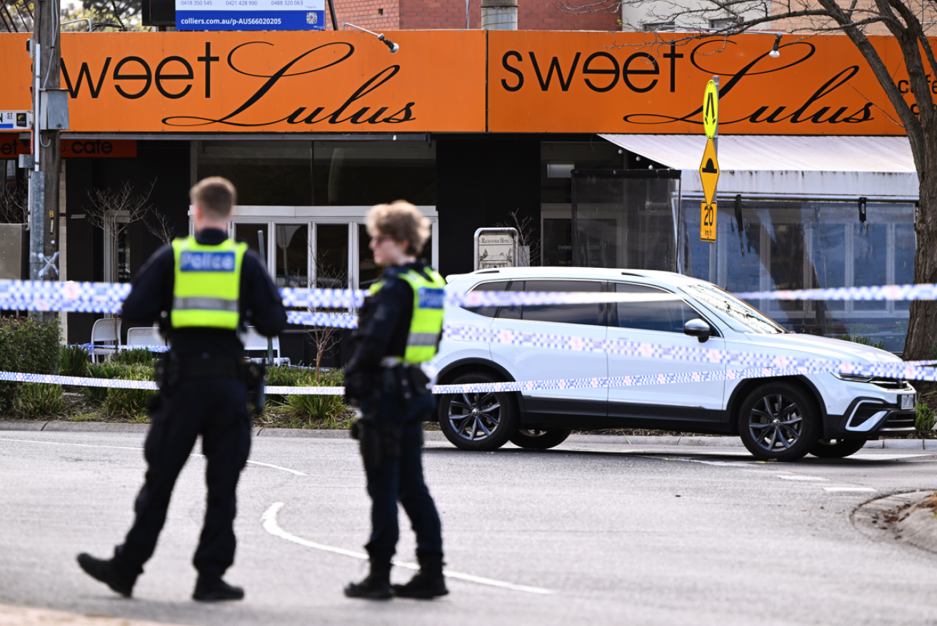 Sealed off with crime-scene tape, police keep spectators away from the scene of the apparent gangland rubout.