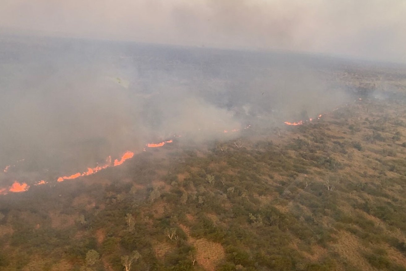 A Northern Territory bushfire has broken containment lines and burnt more than 10,000 square kilometres.