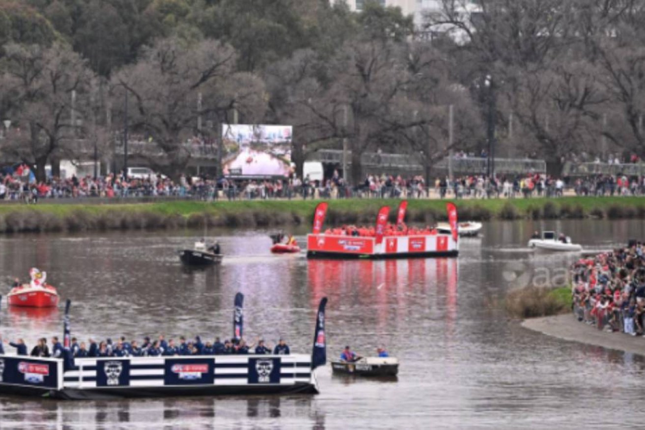 Fans watch as Geelong and Sydney players take part in the 2022 grand final parade on the Yarra.