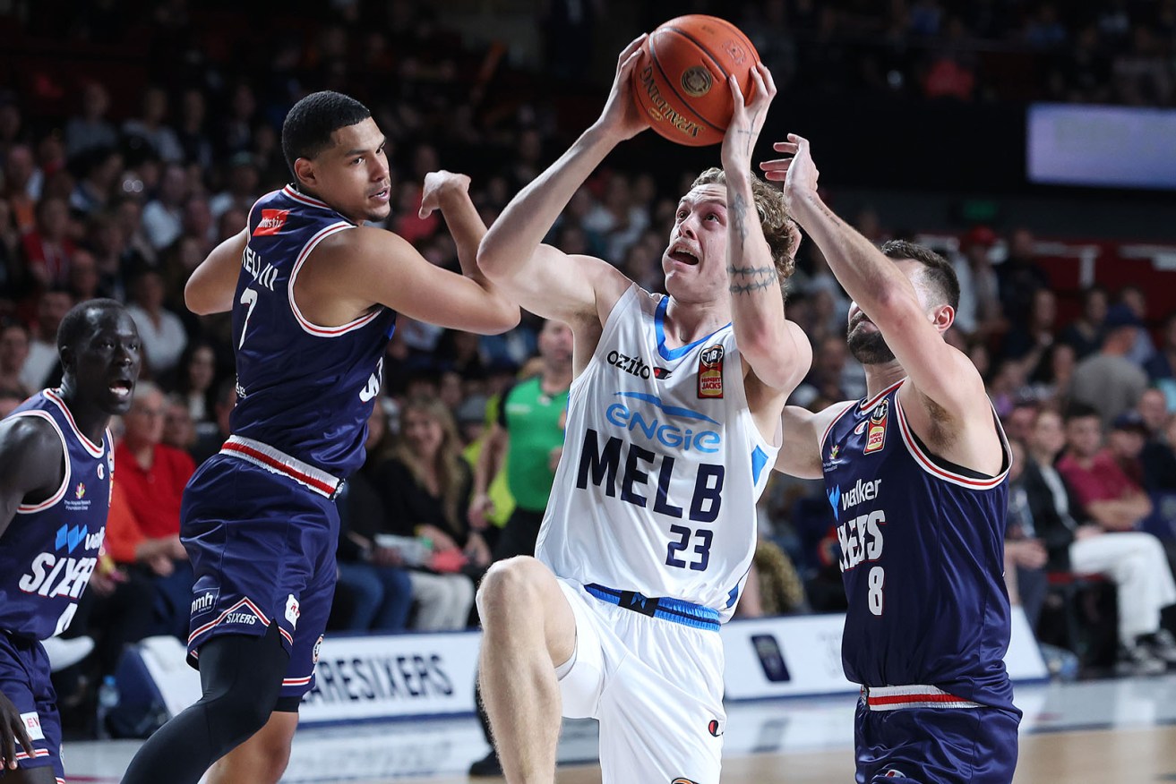 Melbourne United’s Luke Travers squeezes between 36ers duo Issac Humphries and Trey Kell III in Adelaide on Sunday.