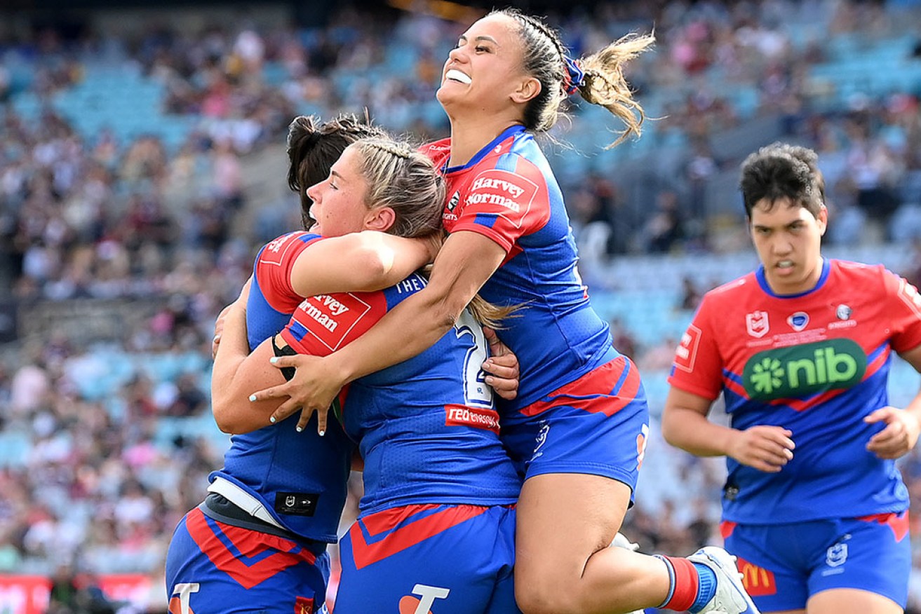 Newcastle teammates mob Shanice Parker after her try in the NRLW grand final at Accor Stadium on Sunday.