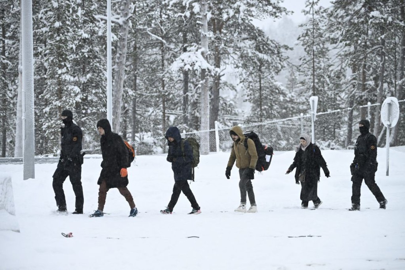 Finnish border guard officers escort migrants crossing from Russia. 