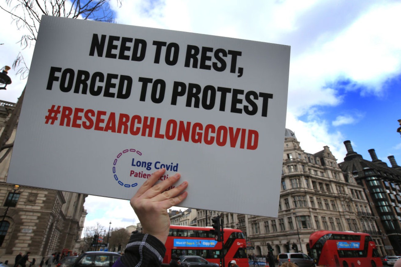 A protester holds up a placard demanding research into Long COVID-19. Photo: Getty