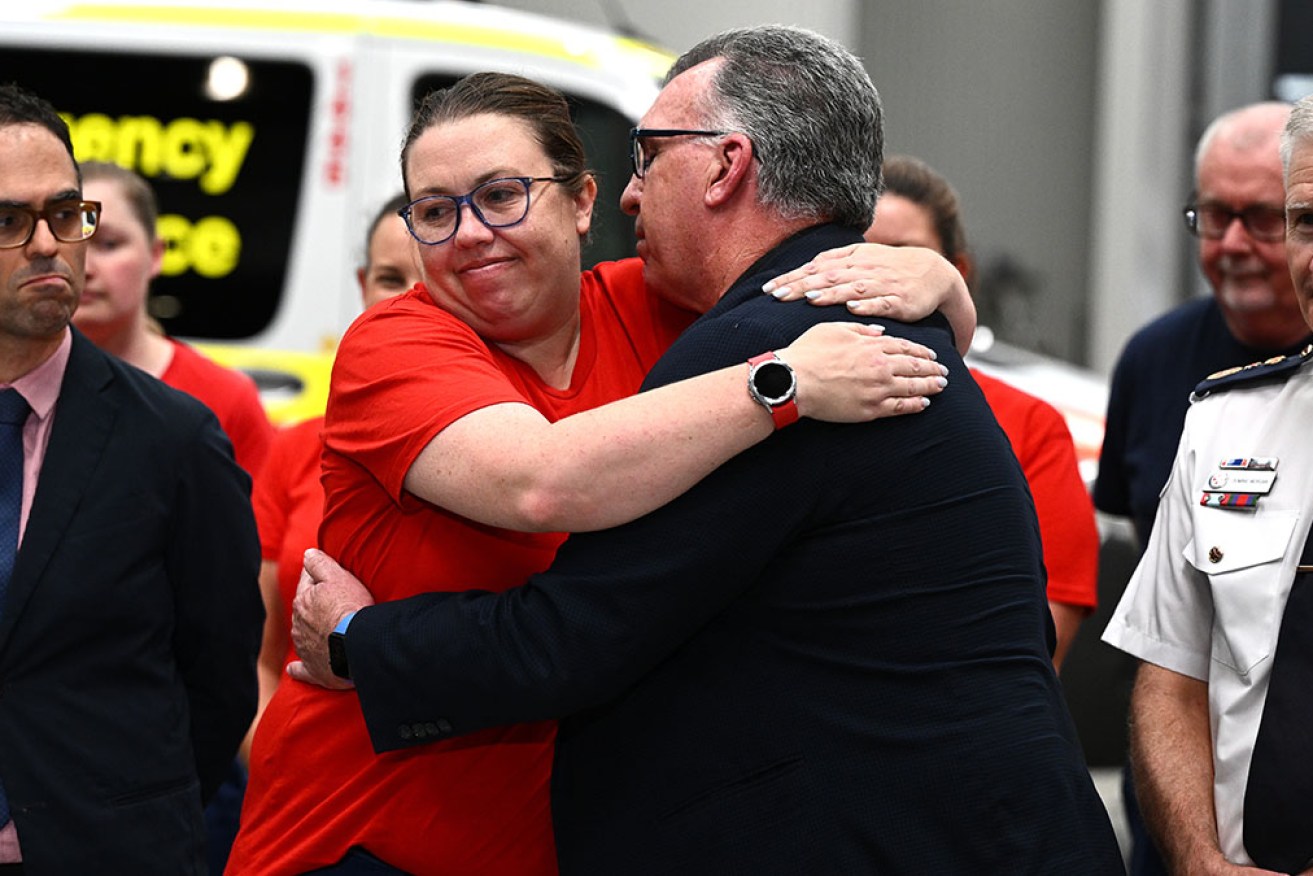 HSU secretary Gerard Hayes hugs paramedic Tess Oxley as NSW Treasurer Daniel Mookhey looks on.