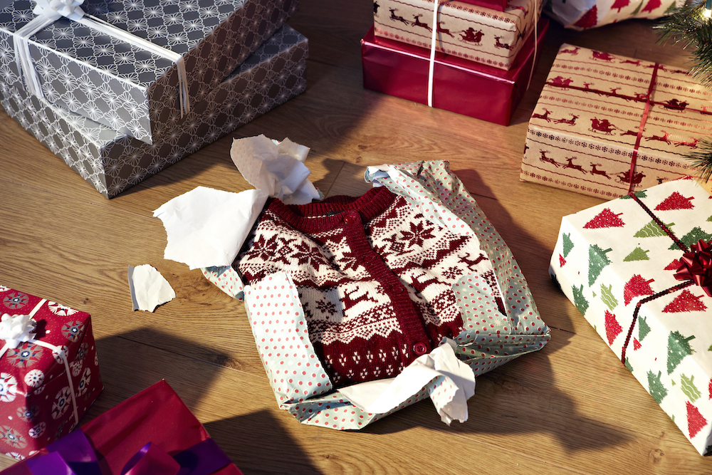 Unwrapped christmas present revealing woollen jumper and other presents