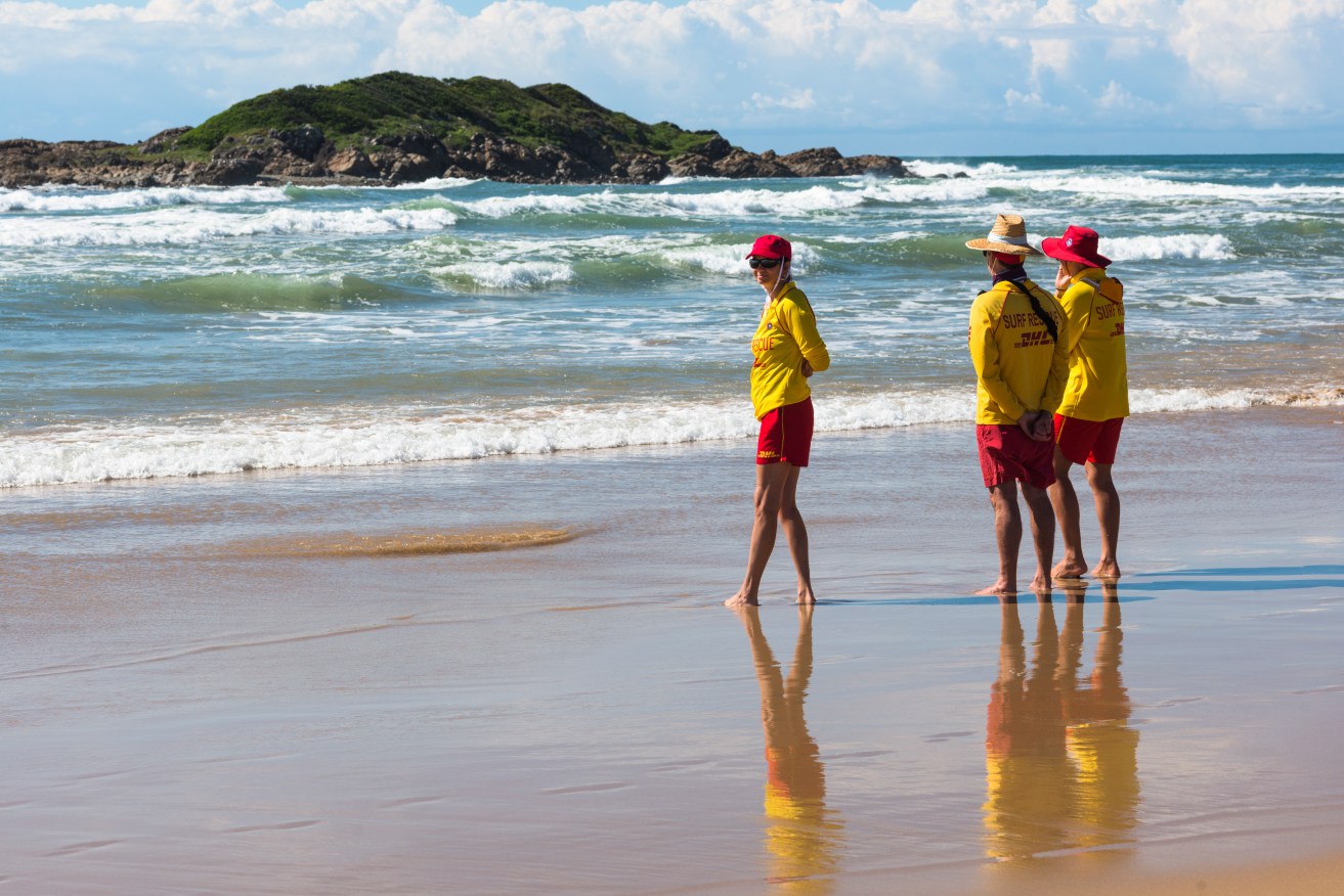 A woman has died after being caught in a rip while swimming with a child who survived the ordeal.