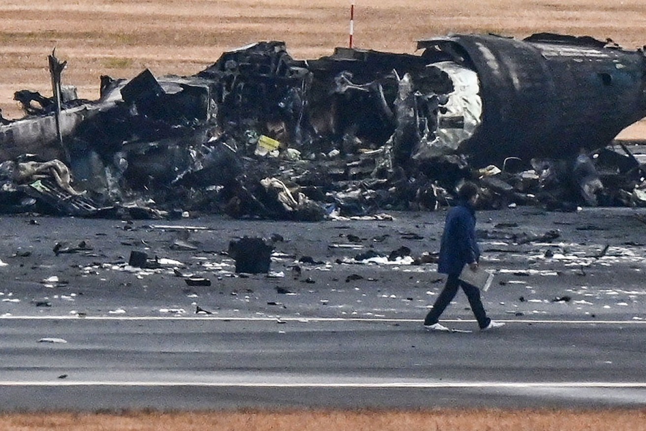 An official looks at the wreckage of a Japan coast guard plane on the tarmac at Haneda airport in Tokyo on Wednesday.