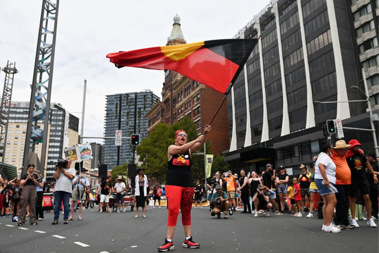 A protester waves an Australian Aboriginal flag during the annual "Invasion Day" protest march through the streets of Sydney on Australia Day.