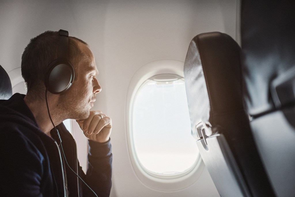pictured is a man with headphones on a flight