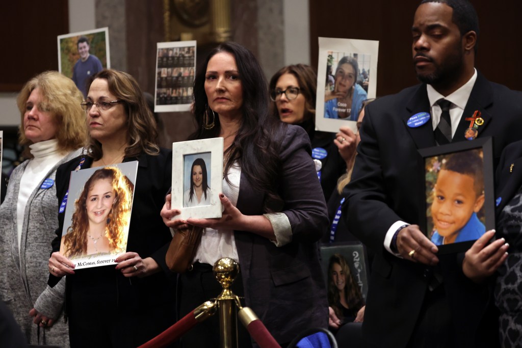 Audience members hold photos of loved ones during a Senate Judiciary Committee hearing at the Dirksen Senate Office Building on January 31, 
