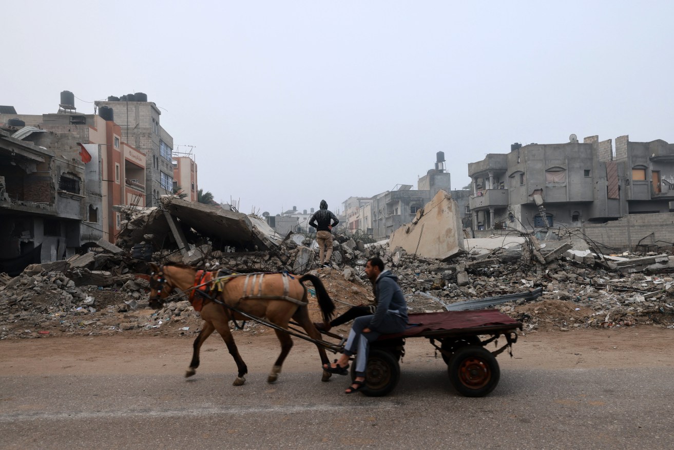 A man rides a horse-pulled cart along a street ravaged by Israeli bombing in Rafah in the southern Gaza Strip.