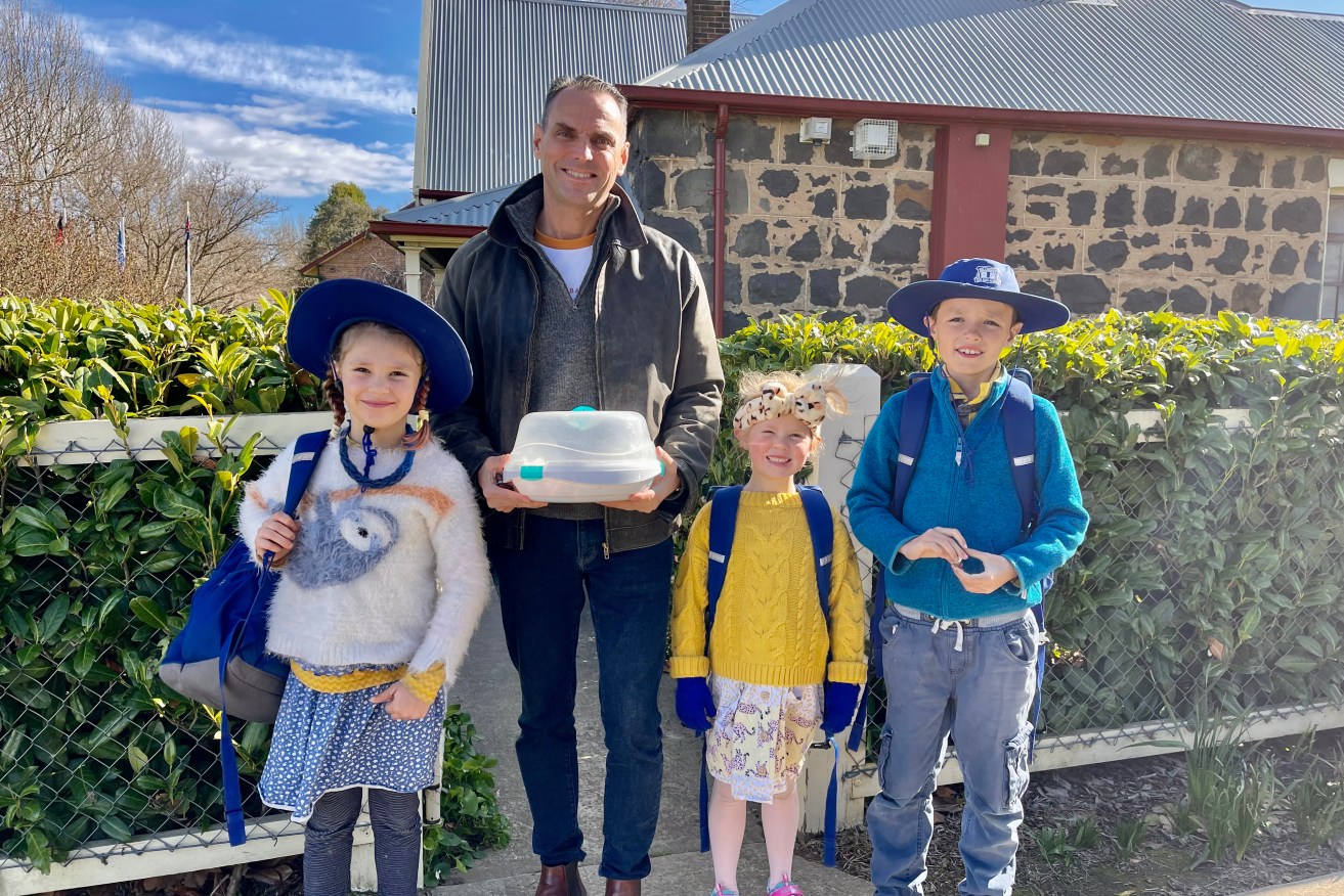 Daniel Duggan posing with three of his children outside their primary school shortly before his surprise arrest in October 2022 in Orange