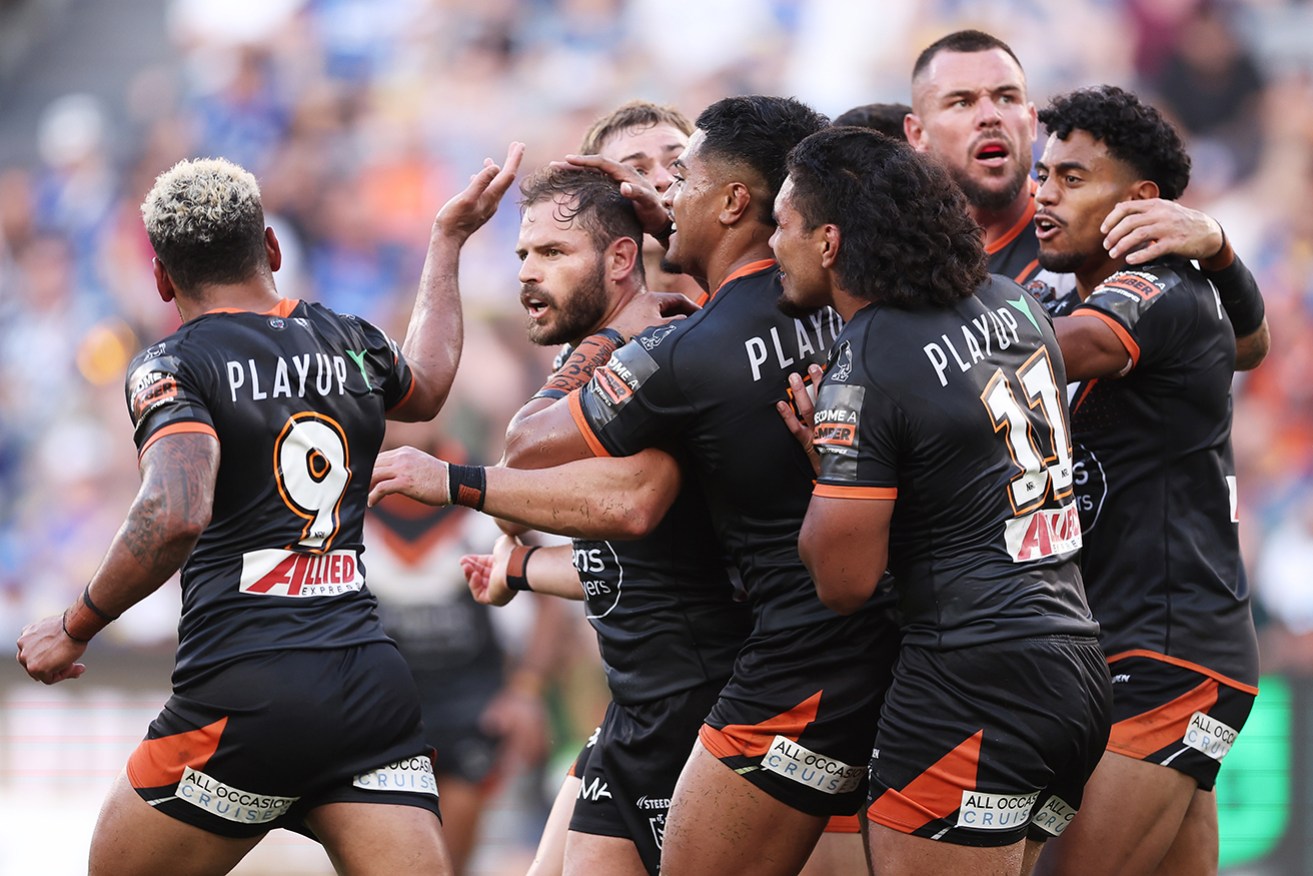 Wests Tigers’ Aidan Sezer celebrates with teammates after kicking a winning field goal on Monday.