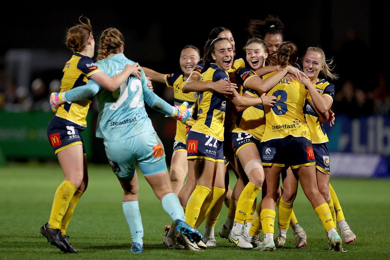 Mariners teammates mob goalkeeper Casey Dumont after their shootout win over Melbourne Victory.