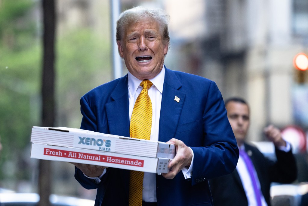 Republican presidential candidate former U.S. President Donald Trump carries boxes of pizza for the FDNY Engine 2, Battalion 8 firehouse on May 02, 2024 in New York City.