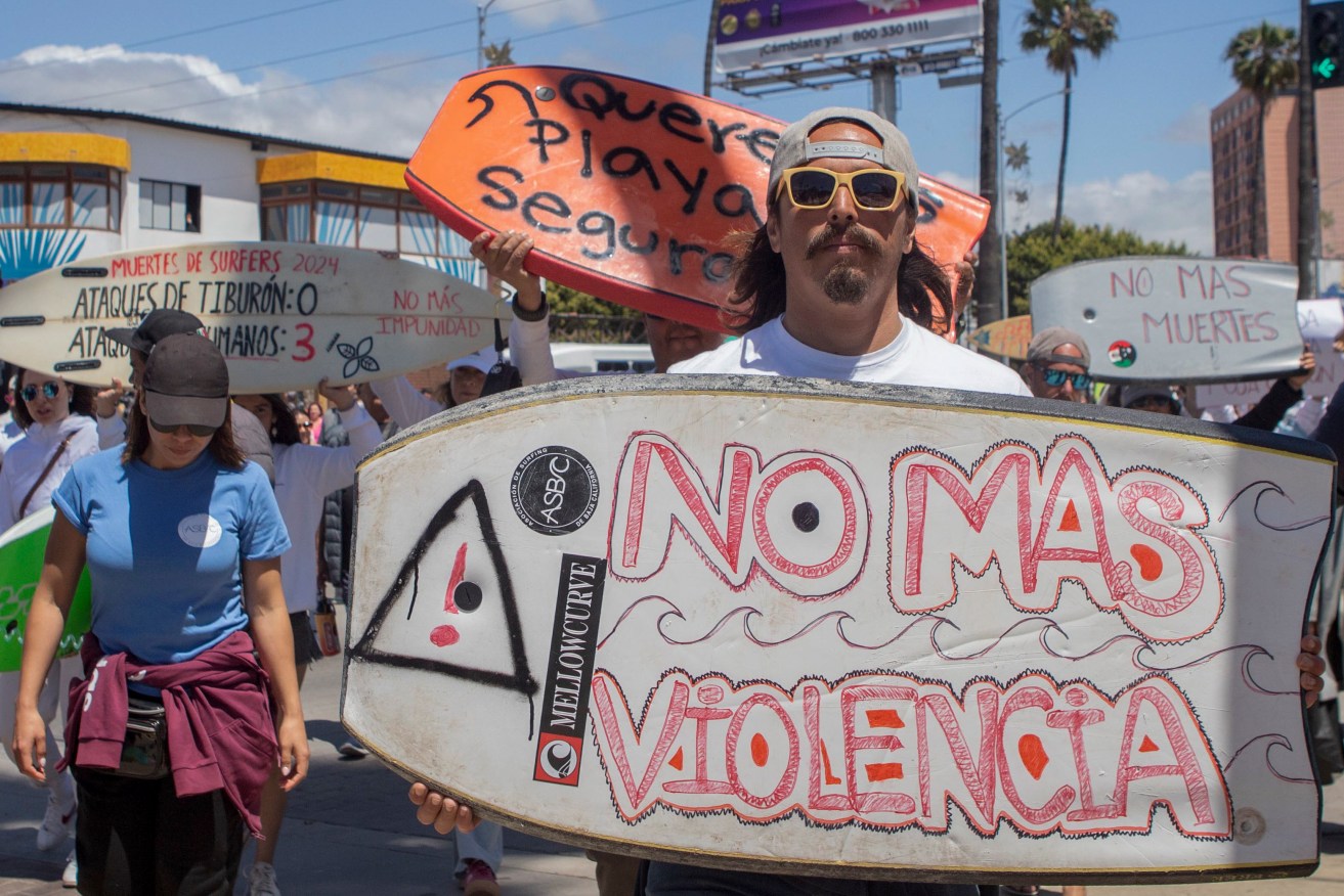 At a protest in Ensenada, Mexico, over the deaths over two Australian brothers, a man holds a board that states: 'No more violence'.