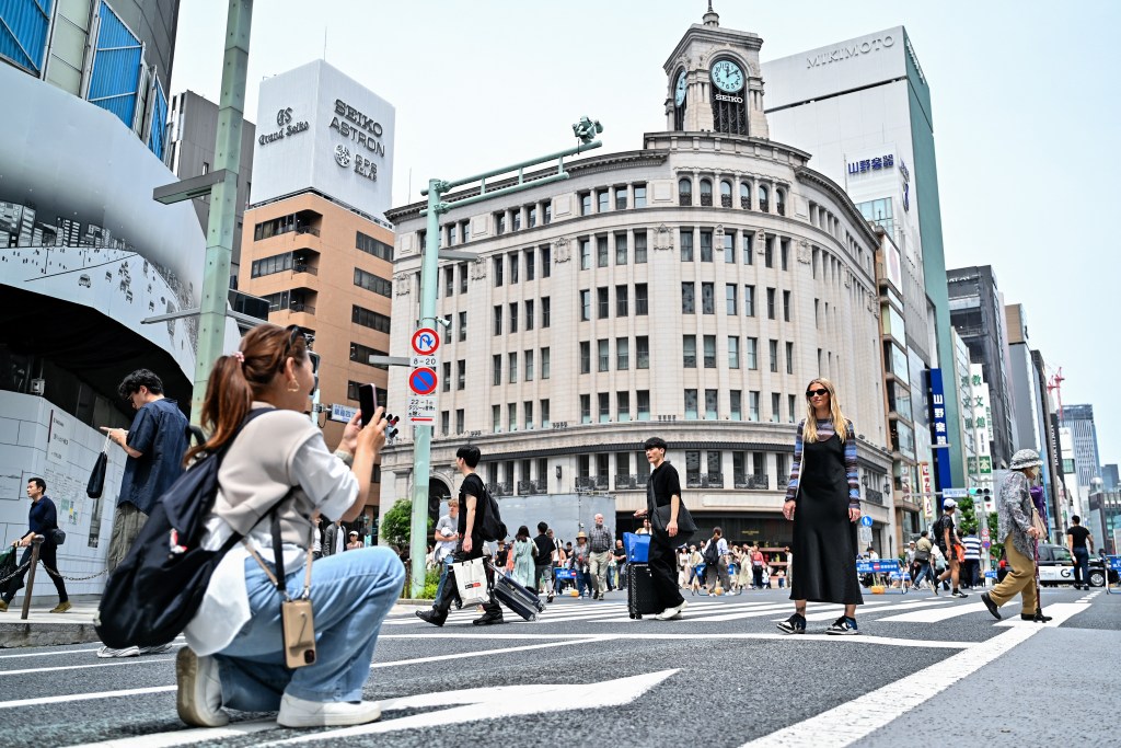 A woman (R) poses for a photo at the main intersection in the shopping district of Ginza 