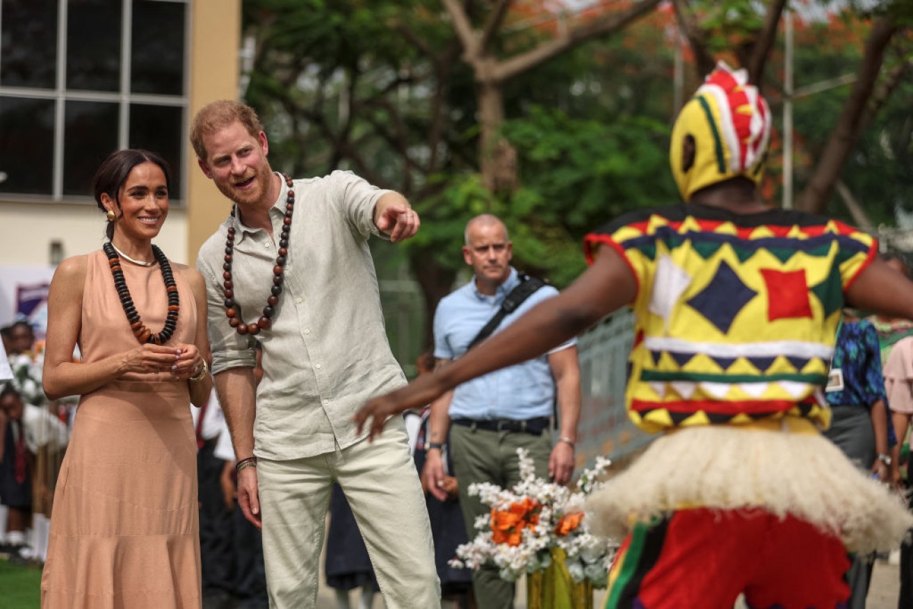 Prince Harry and wife Meghan were greeted by dancers as they arrive at the Lightway Academy in Abuja, Nigeria, on Friday. 