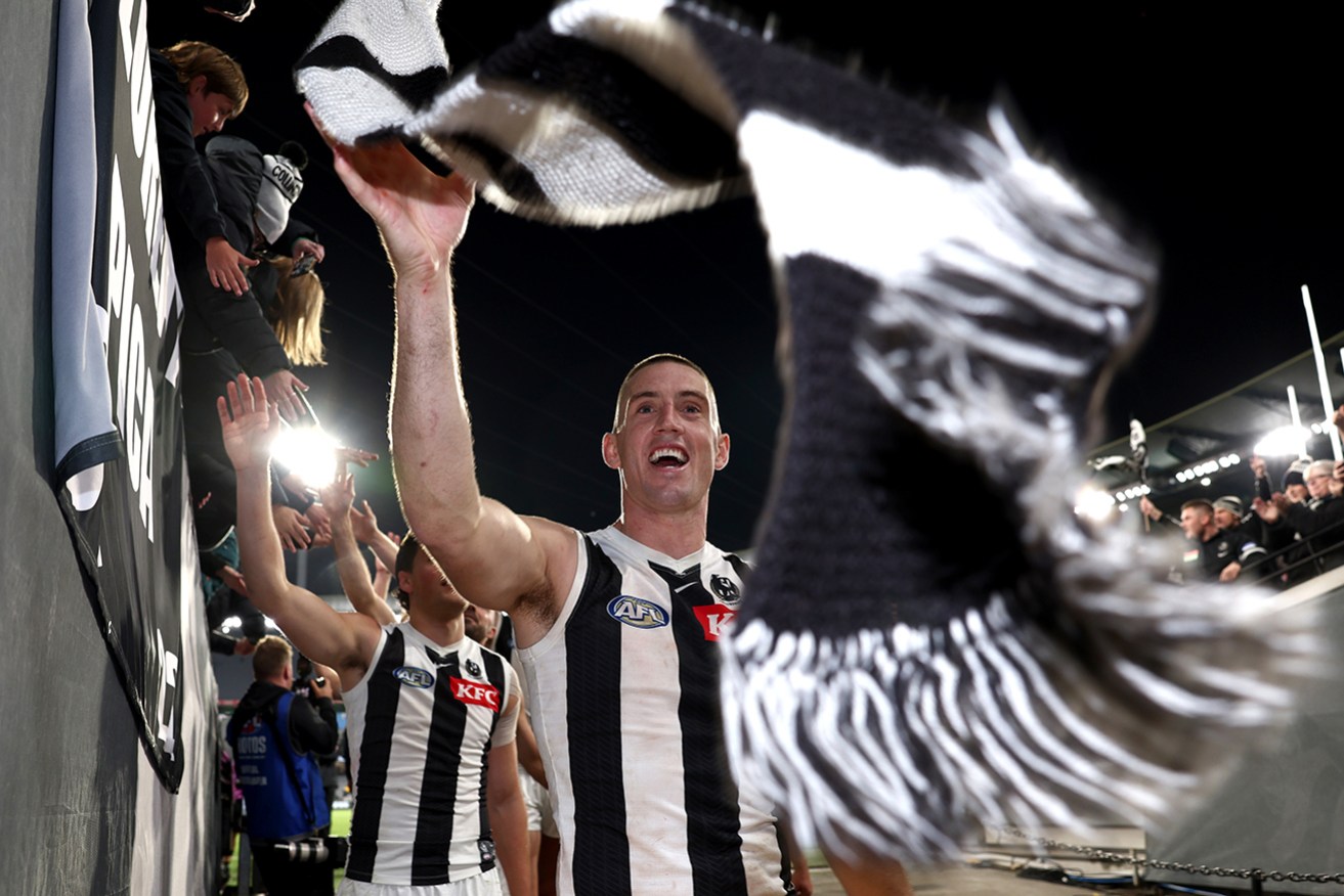 Collingwood’s Darcy Cameron high-fives fans at the MCG.