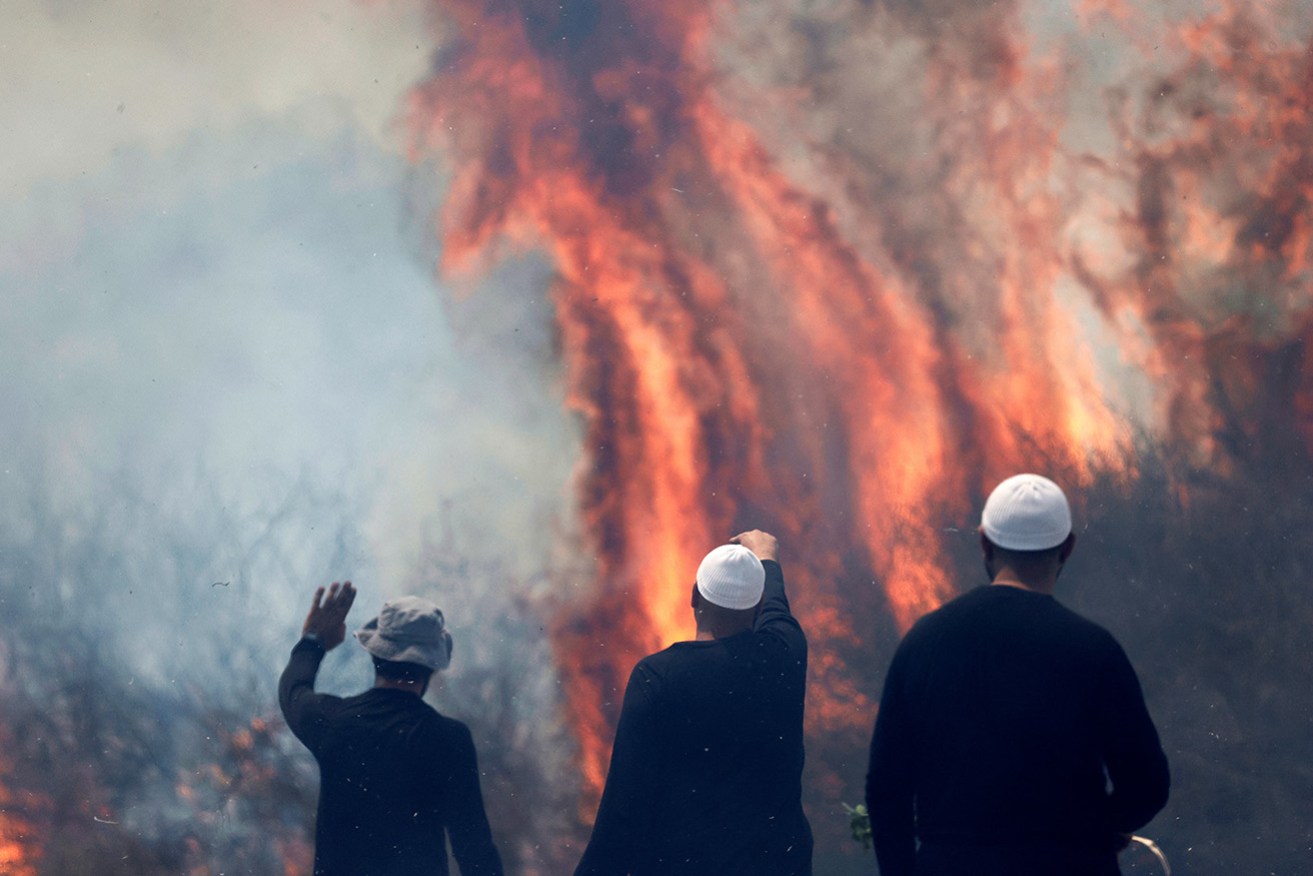 Druze men watch the flames burning a field after rockets launched from southern Lebanon landed on the Banias area in the Israel-annexed Golan Heights on the weekend.