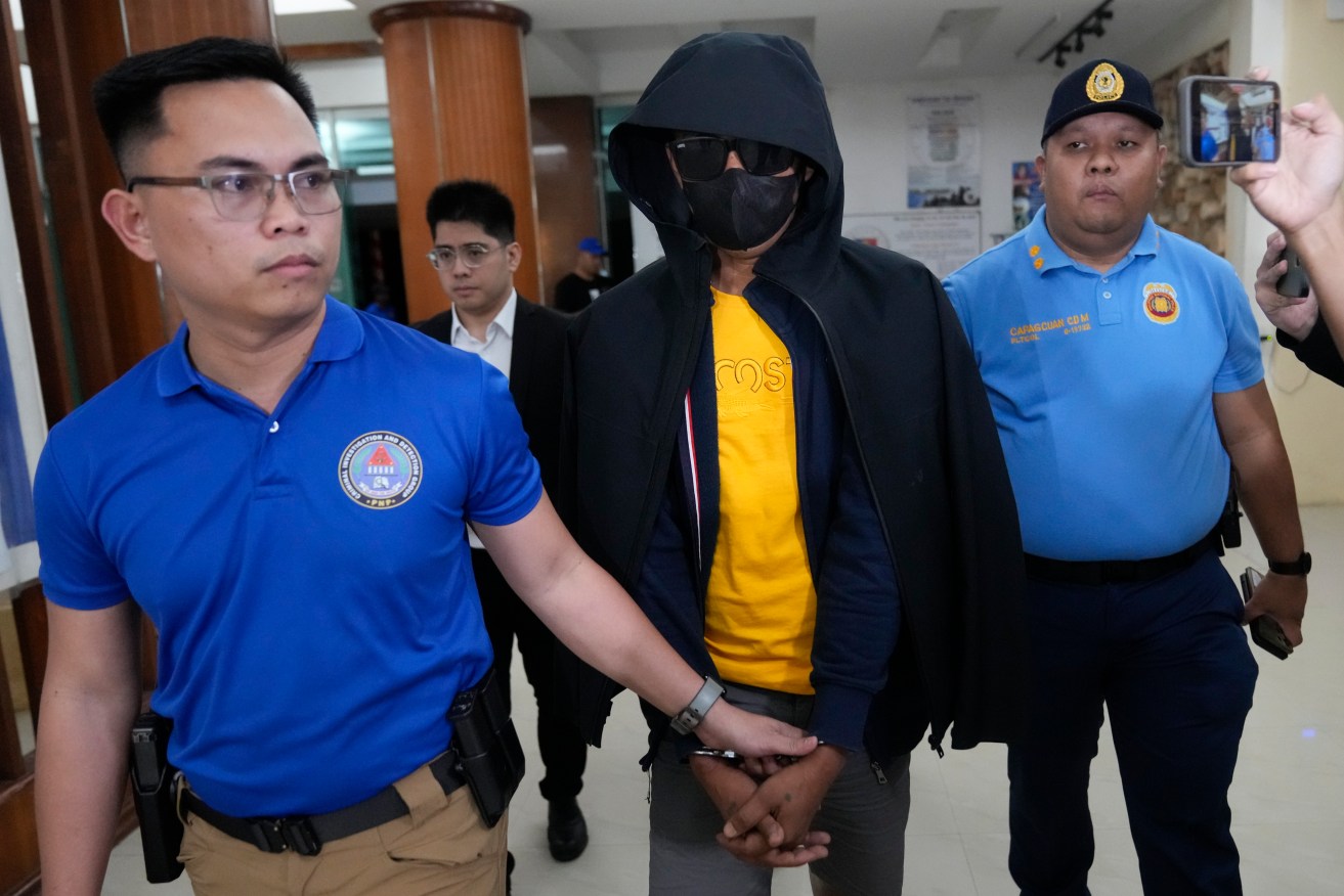 The unidentified suspect in the killings of two Australians and another woman was paraded for the media on Wednesday. Photo: AAP
