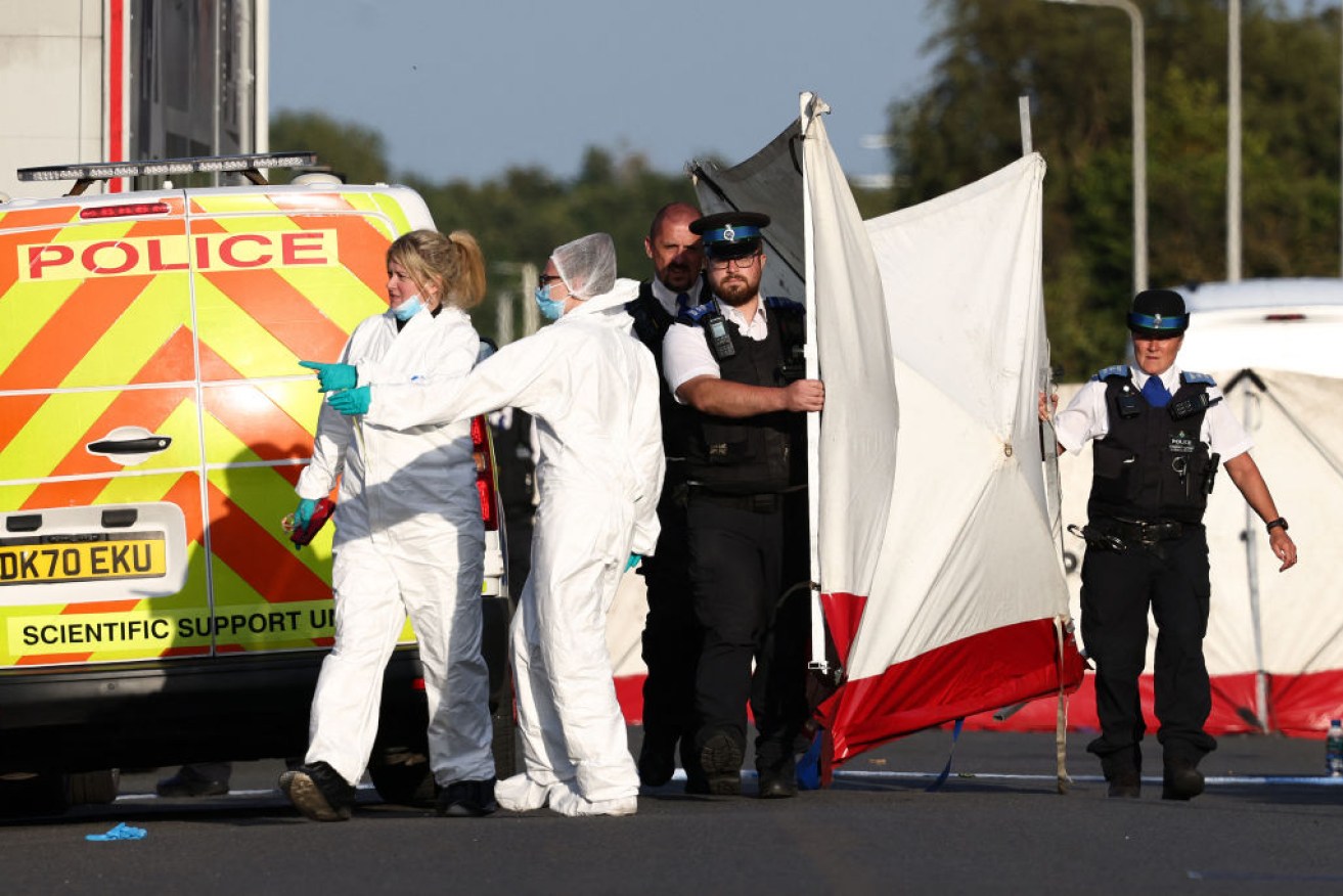 Police officers and forensic personnel put up a fence on Hart Street in Southport.