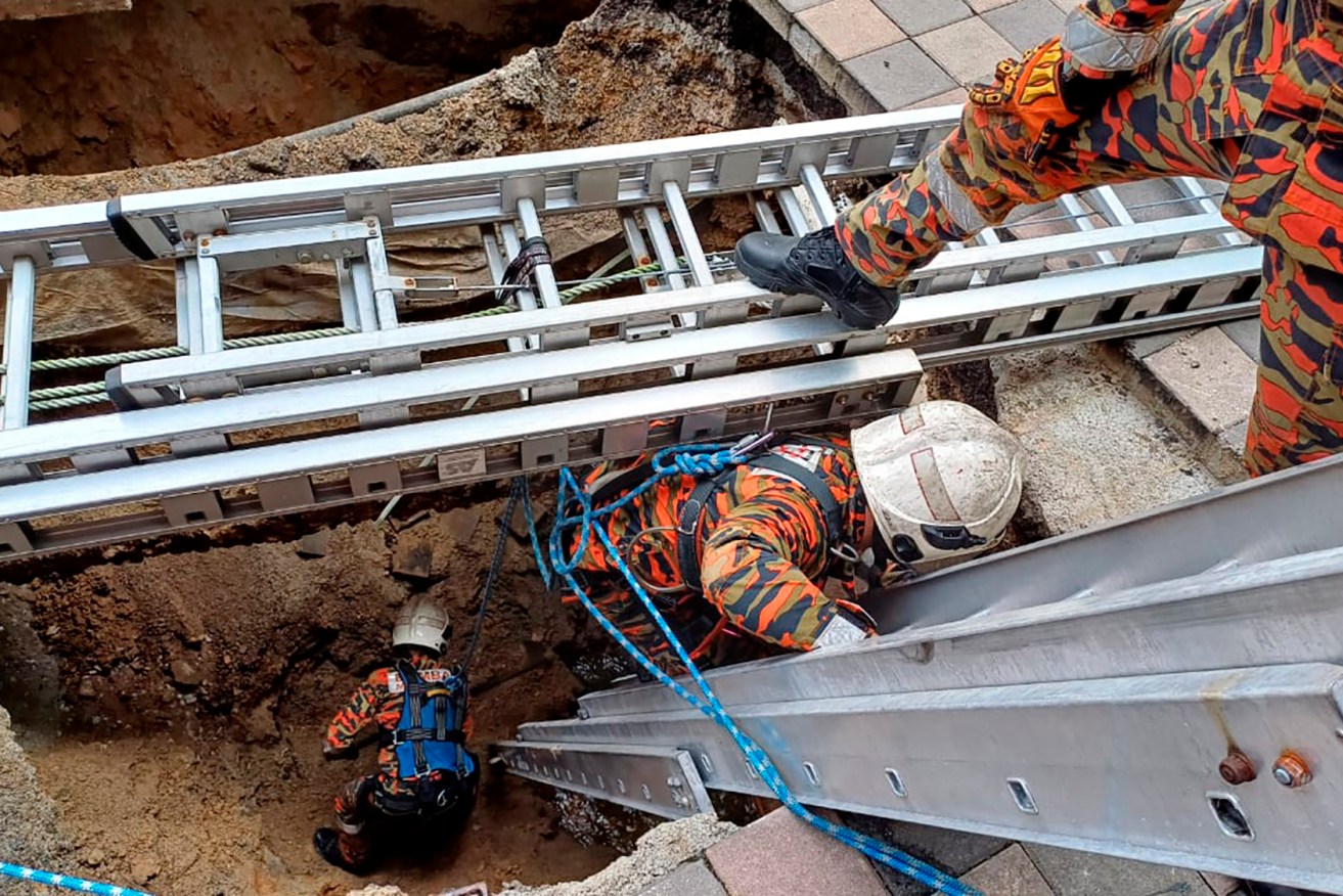 Rescuers look for the woman who disappeared while walking on a footpath in Kuala Lumpar.