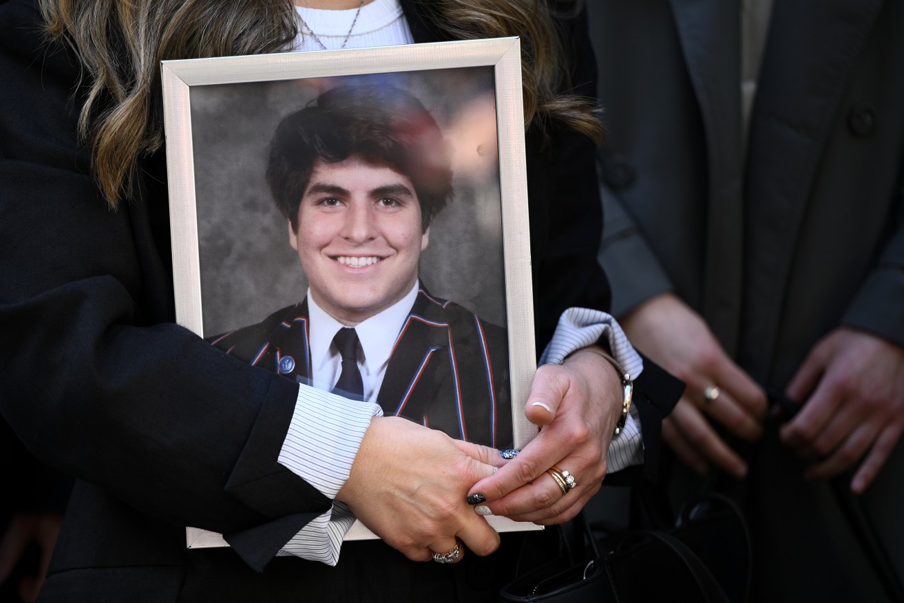 A supporter holds a portrait of James Tsindos outside the Coroners Court of Victoria.