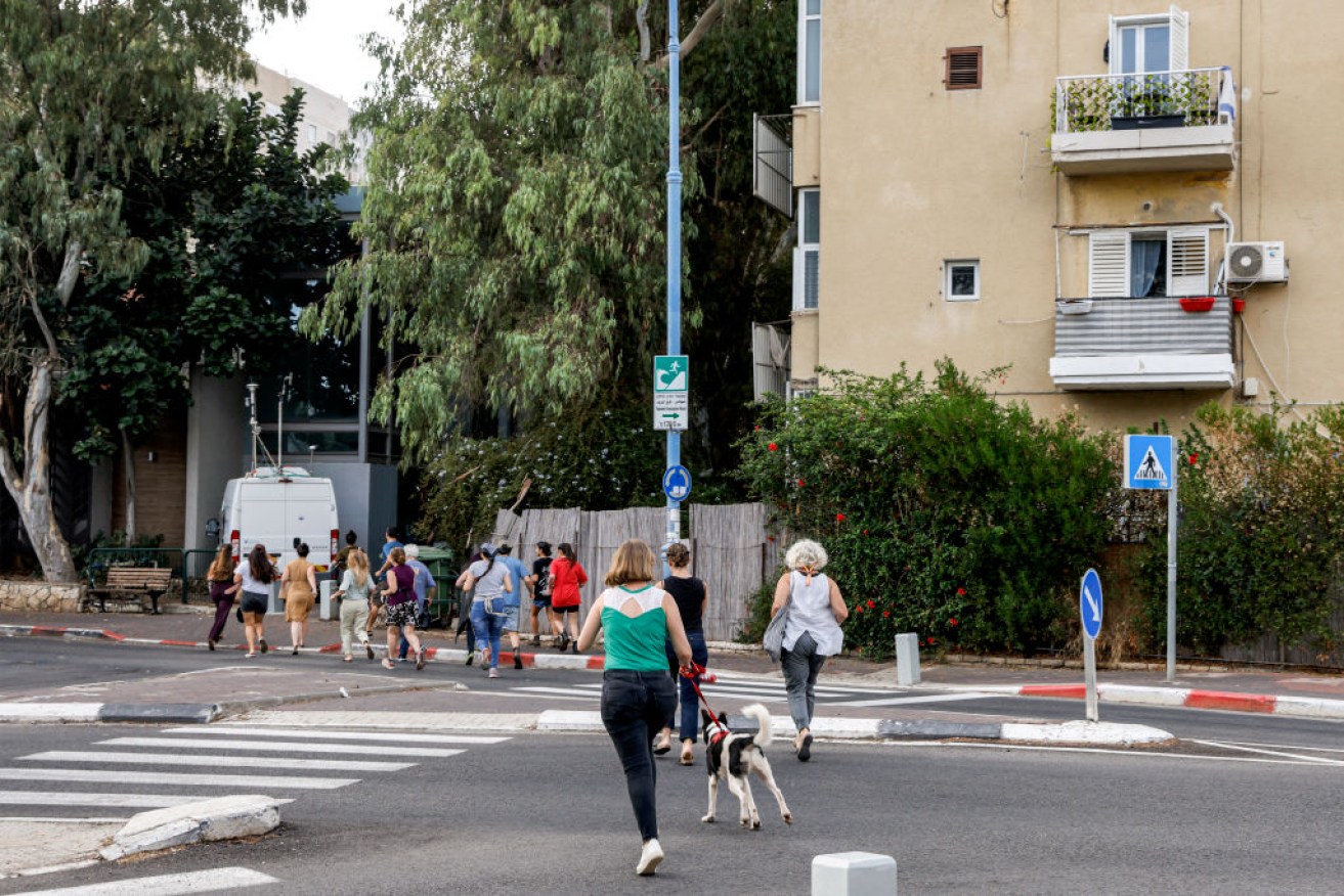 People run to seek refuge in a bomb shelter as sirens wail to warn of incoming rockets in Israel's northern city of Haifa.