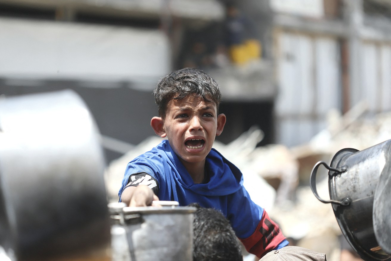 Desperation as a Palestinian child waits to receive food at a distribution centre.