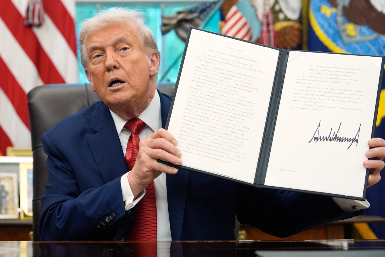 President Donald Trump holds a signed executive order for TikTok's transfer to US owners.