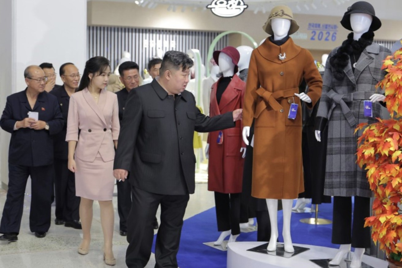 Kim Jong Un inspects a women's coat at a clothing exhibition.